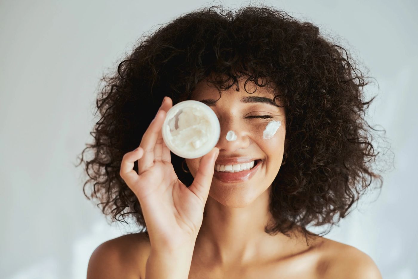 Smiling woman holding a jar of skincare cream